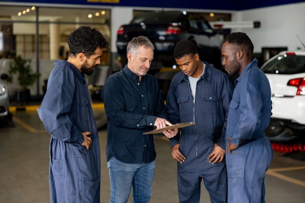 Latin American supervisor talking to a group of mechanics at an auto repair shop